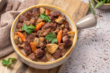 Beef bourguignon stew with vegetables. Grey background.