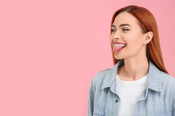 Happy woman showing her tongue on pink background. Space for text