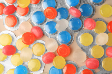 Blisters and many colorful cough drops as background, top view