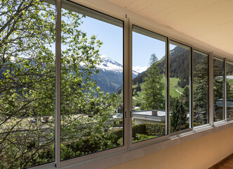 View from the glazed loggia to the green landscape and snowy mountains