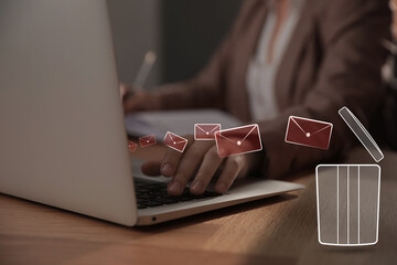 Woman working at table, closeup. Envelopes flying from laptop into trash bin, illustration of spam...
