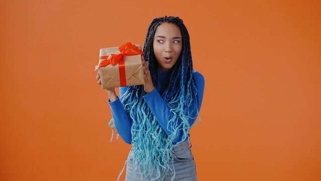 Young African American woman shakes box with present