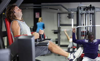 Fototapeta na wymiar Caucasian man training on captains chair in gym