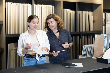 Man and woman together choosing bathroom tile patterns in hardware store