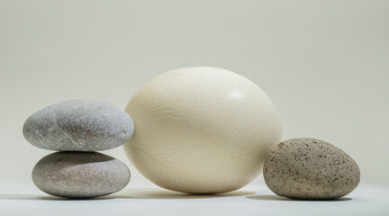 Fototapeta na wymiar oval stones and ostrich egg for product presentation podium background on white background