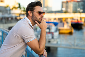 Portrait of handsome male model outdoor. Stylish man dressed in polo. Fashion male posing on the street background. Urban style. Young man walk through the city. Wealthy businessman posing next to