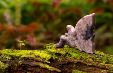 Lepidolite Fairy Sitting on a Fallen Tree Trunk with Green Moss Nature Background