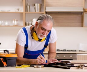 Aged contractor repairman working in the kitchen