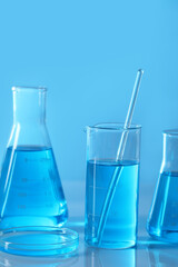 Different laboratory glassware with light blue liquid on table