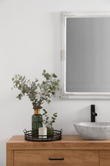 Fototapeta na wymiar Beautiful eucalyptus branches near vessel sink on bathroom vanity. Interior design