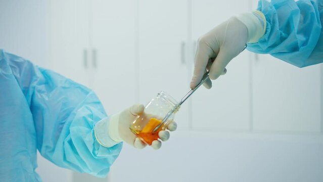 nurse in sterile glove hands surgical instruments tweezers wet gauze to surgeon during operation