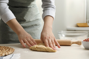 Obraz na płótnie Canvas Woman kneading raw dough at white wooden table, closeup