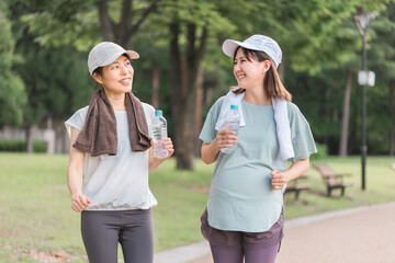 ママ友と散歩する妊婦の若いアジア人女性
