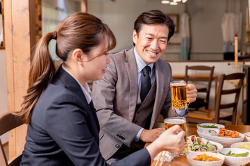 居酒屋で楽しい忘年会・新年会・飲み会・宴会をする仕事仲間・同僚・上司部下の男女
