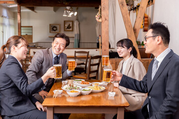 居酒屋で新入社員の歓迎会・飲み会をする上司部下の男女
