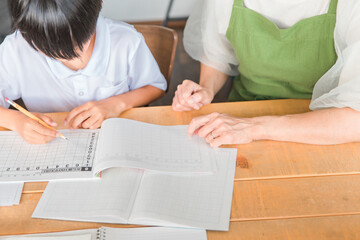 リビングで宿題をする小学生の男の子と母親
