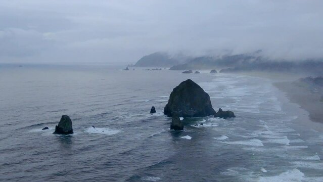 Raining fog breezy Canon Beach Oregon drone aerial cinematic haystacks rock coastline wave cloudy afternoon gray Pacific Ocean Arcadia highway 101 Oswald west stunning ocean slowly left