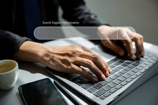 Using a blank search bar, a businessman is browsing the internet and searching for information on his laptop. This stock photo portrays the concept of search engine optimization and networking.