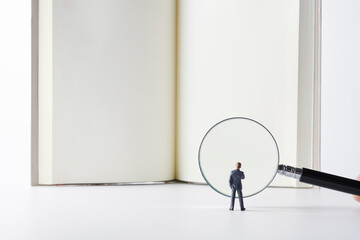 虫眼鏡で本を読むビジネスマン