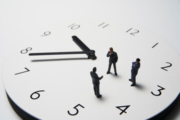 時計の上で話すミニチュアのビジネスマン