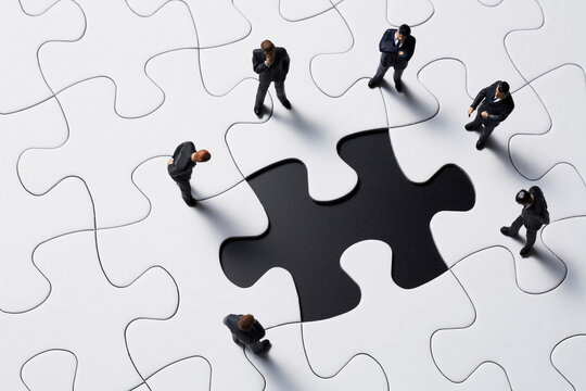パズルのピースを見つめるビジネスマン