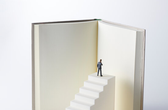 階段の頂上に上り本を読むビジネスマン