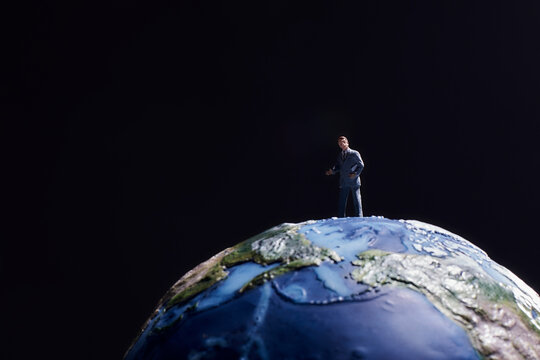 黒い背景に地球の模型とミニチュア人形