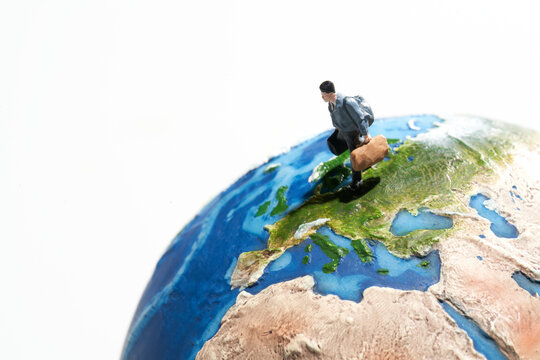 地球の模型の上で旅行をするミニチュア人形