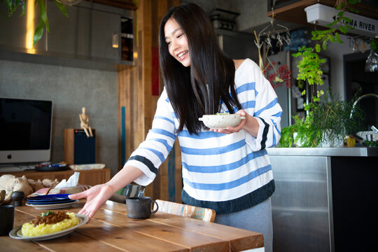 料理の乗ったお皿をテーブルに置いている女性