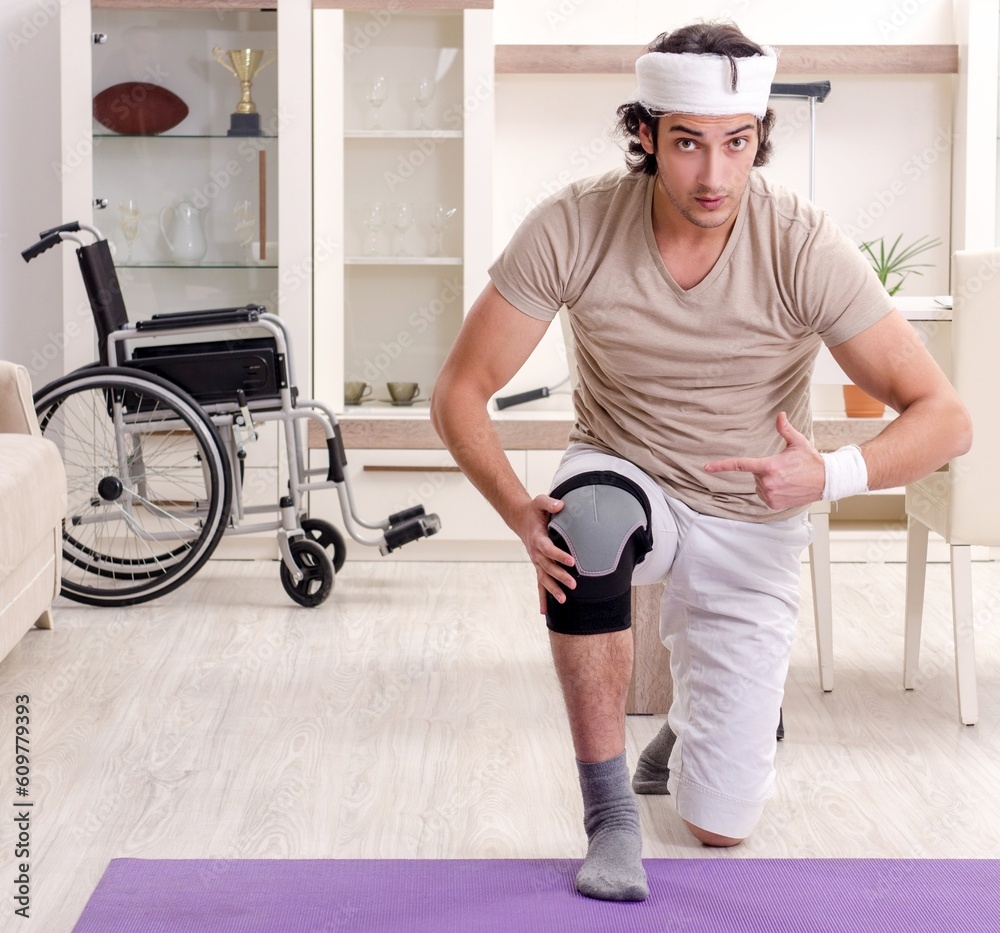 Wall mural injured young man doing exercises at home