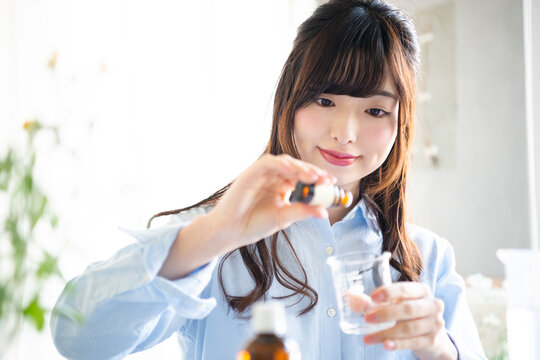 アロマオイルを入れて化粧水を作っている女性