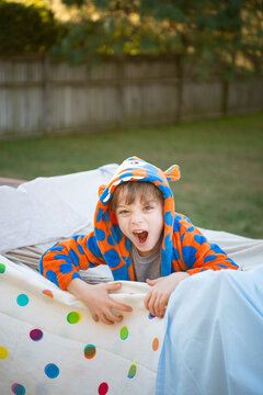 シーツで作ったテントから出ている男の子