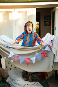 シーツで作ったテントから出ている男の子