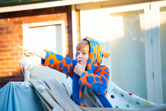 シーツで作ったテントから出て指を指している男の子