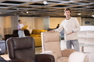 Furniture salesman offering armchairs in furniture store