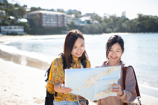 ビーチで地図を見ている女性2人