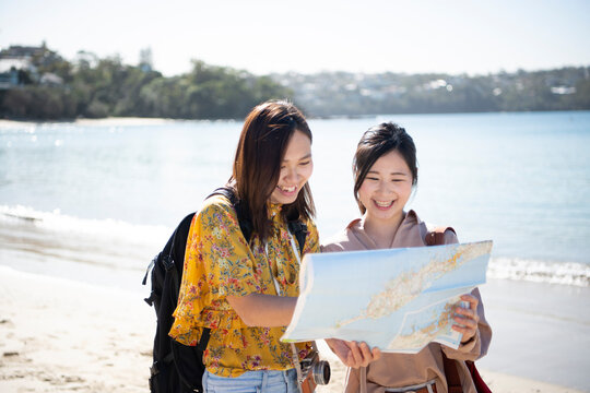 ビーチで地図を見ている女性2人