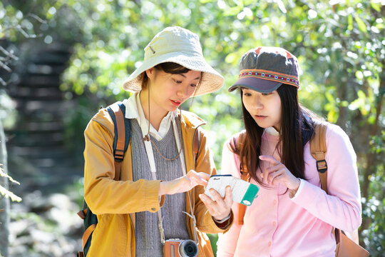 ハイキング中にスマホで地図を見ている女性2人