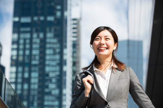 ビル群の中を歩いているスーツ姿の女性