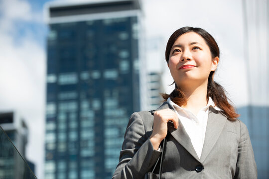 ビル群の中を歩いているスーツ姿の女性