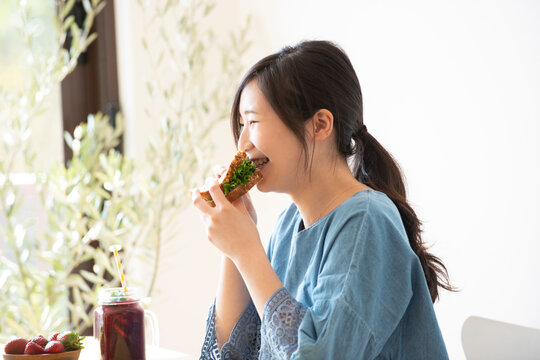 サンドイッチを食べながら笑っている女性
