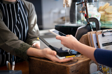 お店でスマホを使って電子決済をしている女性