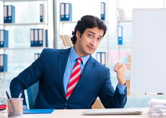 Naklejka premium Young handsome businessman in front of whiteboard