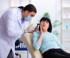 Old woman visiting young doctor laryngologist