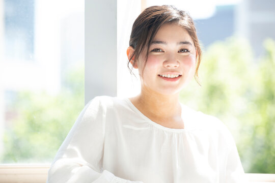 窓辺でこちらを見て笑っている女性