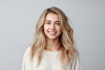 Naklejka premium Headshot of a beautiful blond smiling young woman looking at the camera on gray background. Generative AI