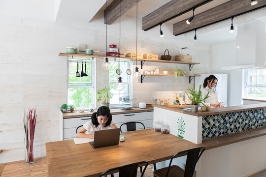 オンライン授業を受ける女の子と家事をする母