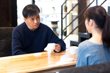 カフェでコーヒーを飲みながら話しをする夫婦