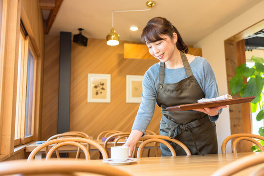 テーブルの片付けをする女性店員