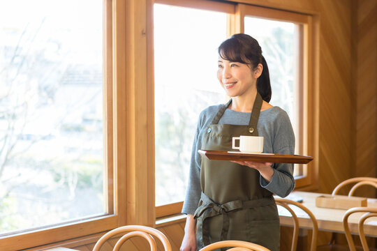 コーヒーを乗せたトレーを持って立つ女性店員